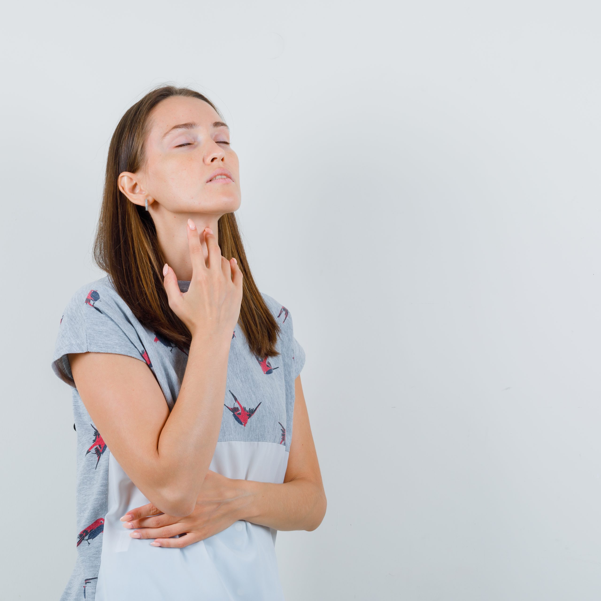 Young woman in t-shirt touching sore throat with fingers , front view.