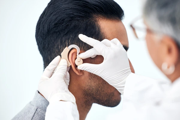A doctor helps a patient to use a hearing aid device