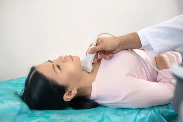 A thyroid specialist performing a thyroid ultrasound on a patient's neck to diagnose a thyroid condition A thyroid specialist performing a thyroid ultrasound on a patient's neck to diagnose a thyroid condition