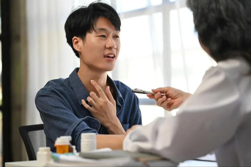 Patient Consultation with Throat Specialist A male patient discussing throat symptoms and medical history with a specialist during a first consultation in Singapore.