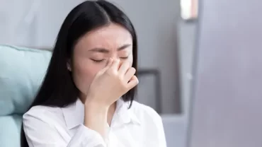 A woman experiencing facial pain and pressure, a common symptom of sinusitis