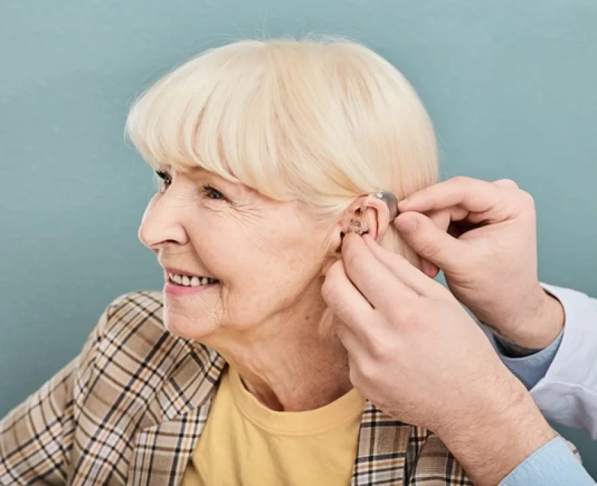 Audiologist fitting a hearing aid for an elderly woman