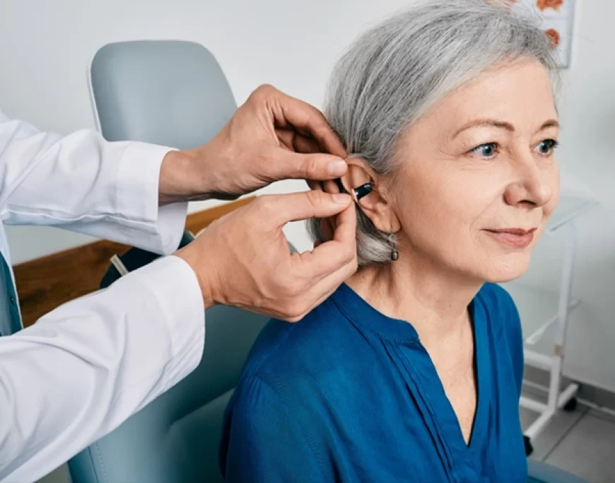 An ENT specialist fitting a hearing aid into the ear of a patient