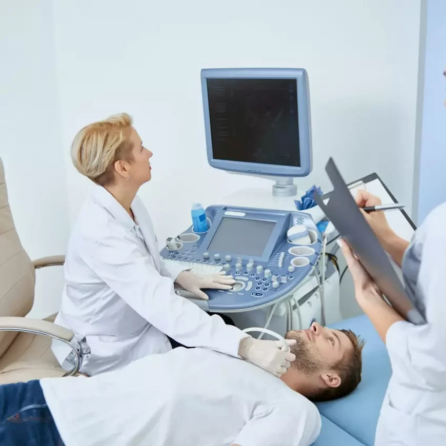 Young man laying on bed during observation on medical concultation in private clinic. Professional doctor good spesialist treating patient with medical equipment with help of young nurse.